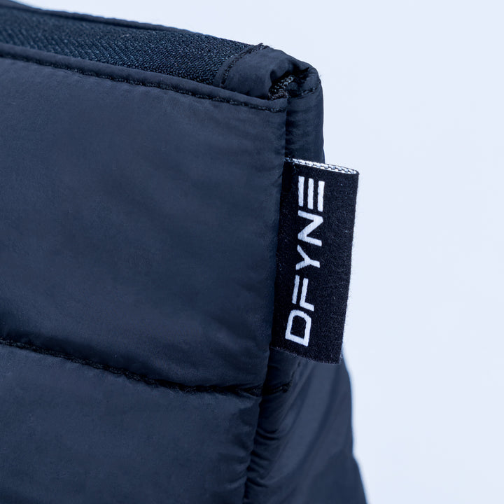 Close-up of dark navy quilted pouch with DEFY logo fabric tag