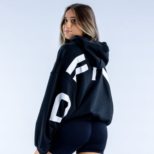 Dark navy hoodie with bold white back logo, hood up, relaxed fit.