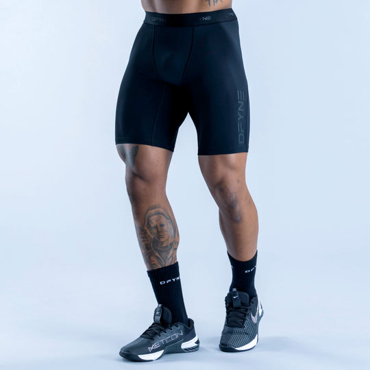 Black compression baselayer shorts with elastic waistband and stitched panel seams