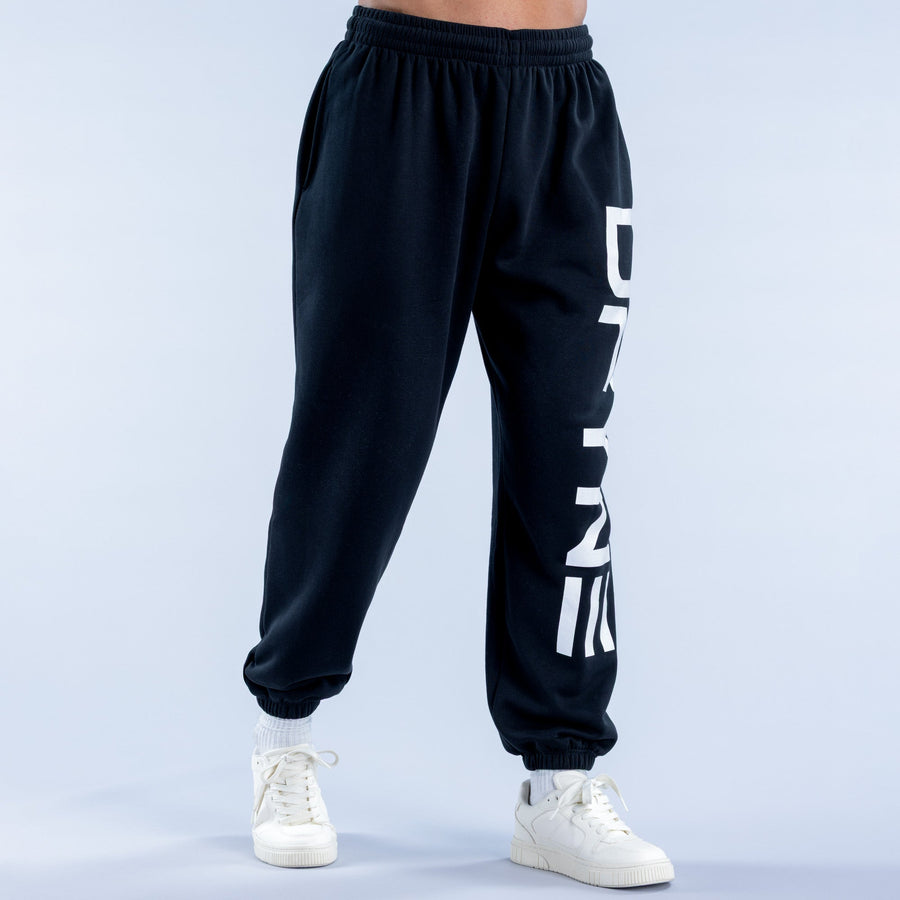 Dark cuffed jogger pants with white vertical logo stripe and ankle cuffs