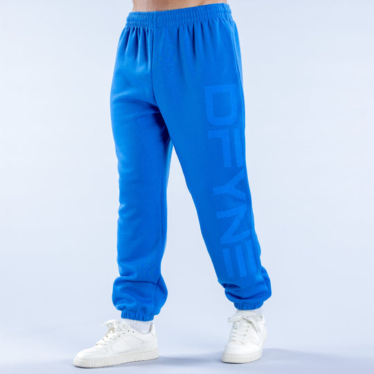 Blue cuffed jogger pants with elastic waistband, side vents, and logo print