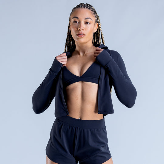 Navy hooded zip-up cropped jacket over black sports bra and athletic shorts set