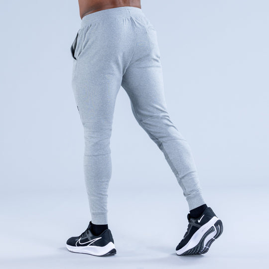 Light gray tapered jogger pants from rear with elastic waistband and drawcord