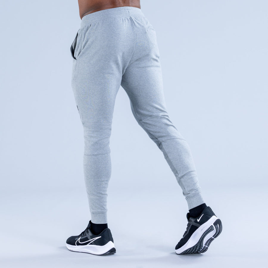 Light gray tapered jogger pants from rear with elastic waistband and drawcord