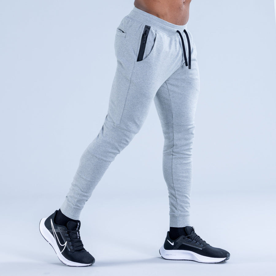Light gray tapered jogger pants with zip pocket detail and drawstring waist