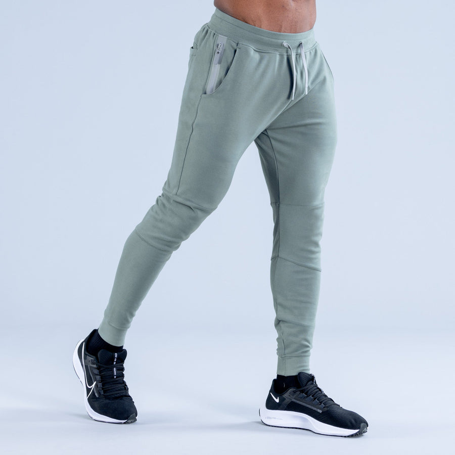 Sage green tapered jogger pants with front zip pocket and drawstring waistband