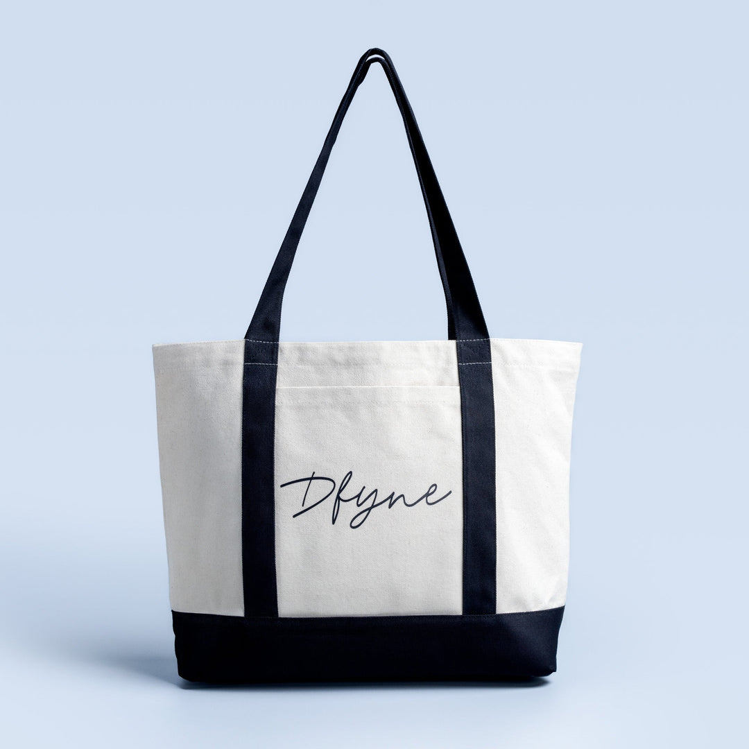 White and black tote bag with black handles and script logo front panel.