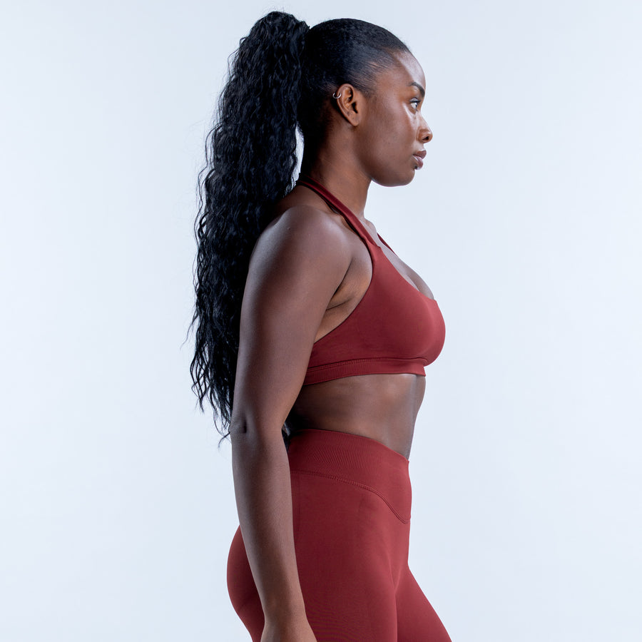 Side view of the red halter sports bra with a scoop neckline