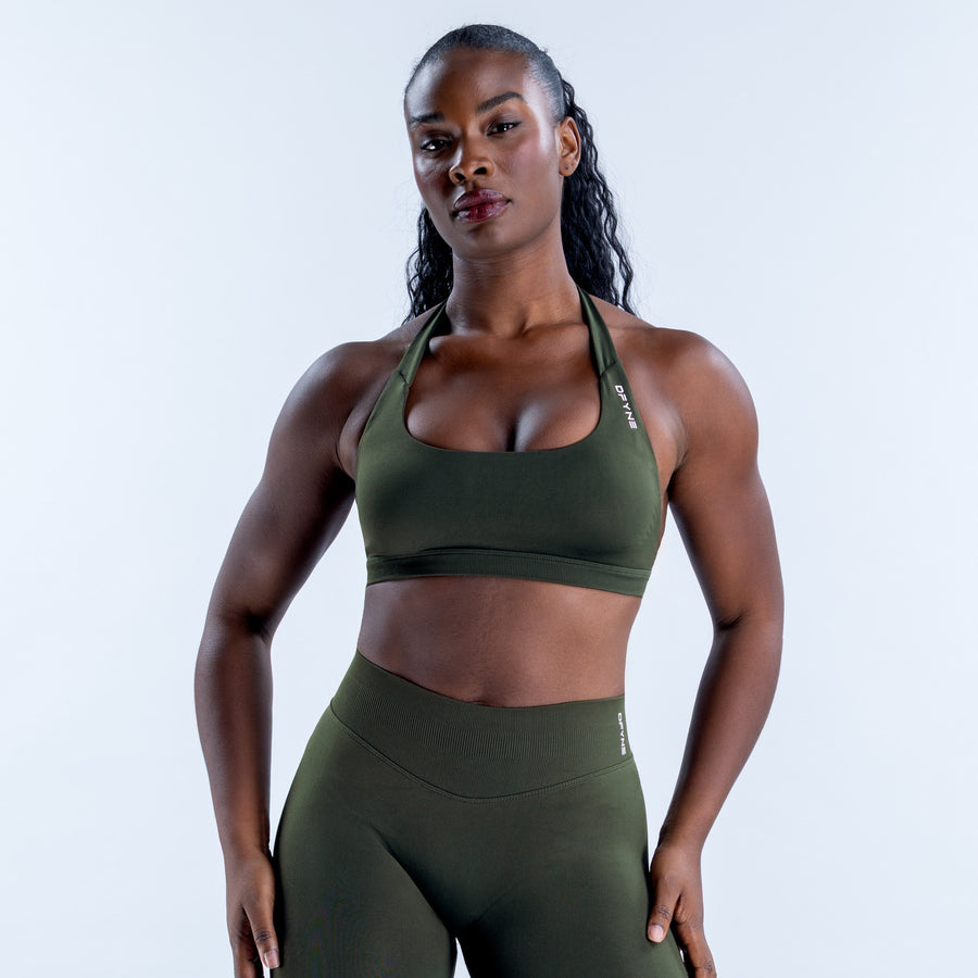 Dark olive sports bra with a scoop neckline, halter straps, and wide underband.