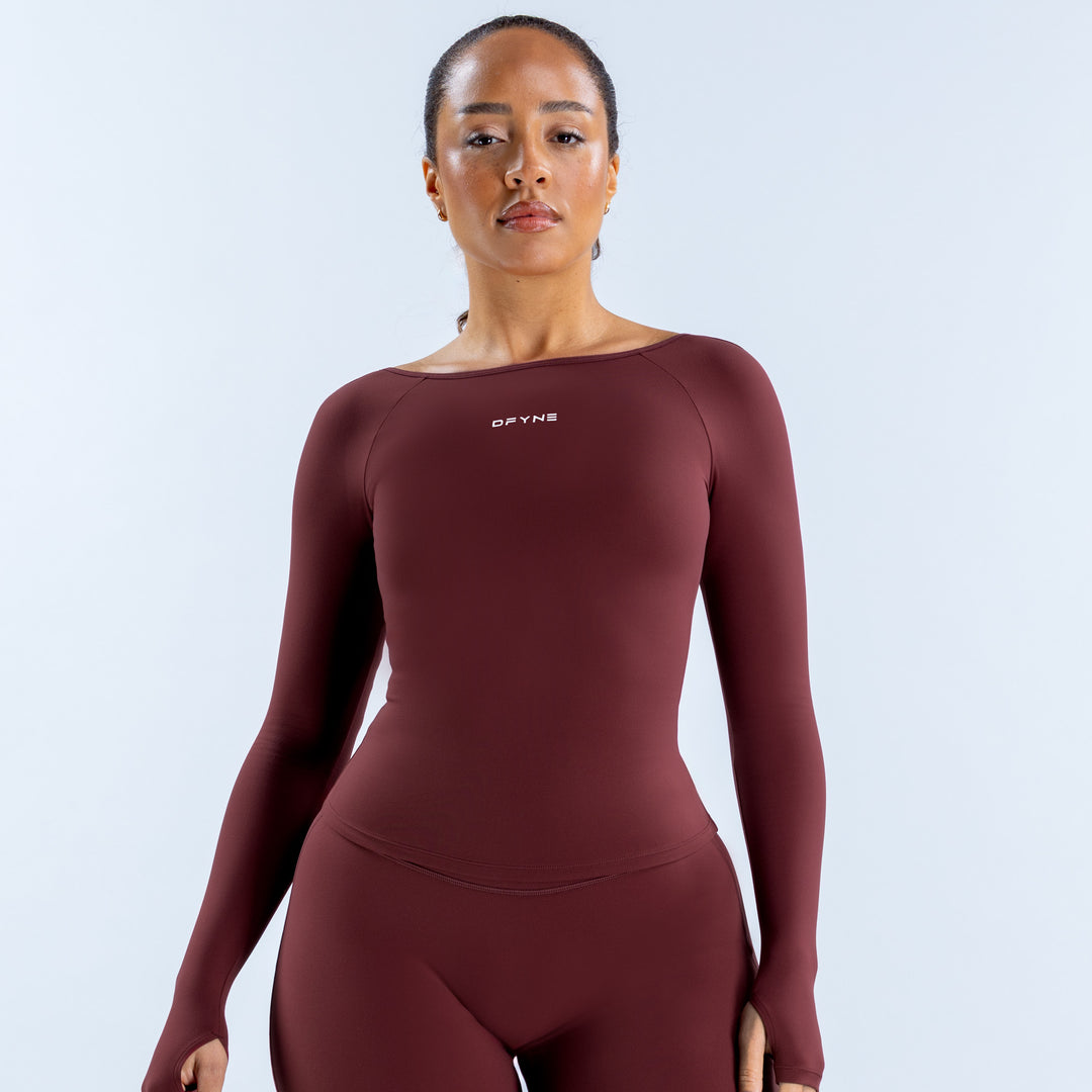 Burgundy long sleeve scoop neck top with a fitted cut and small chest logo