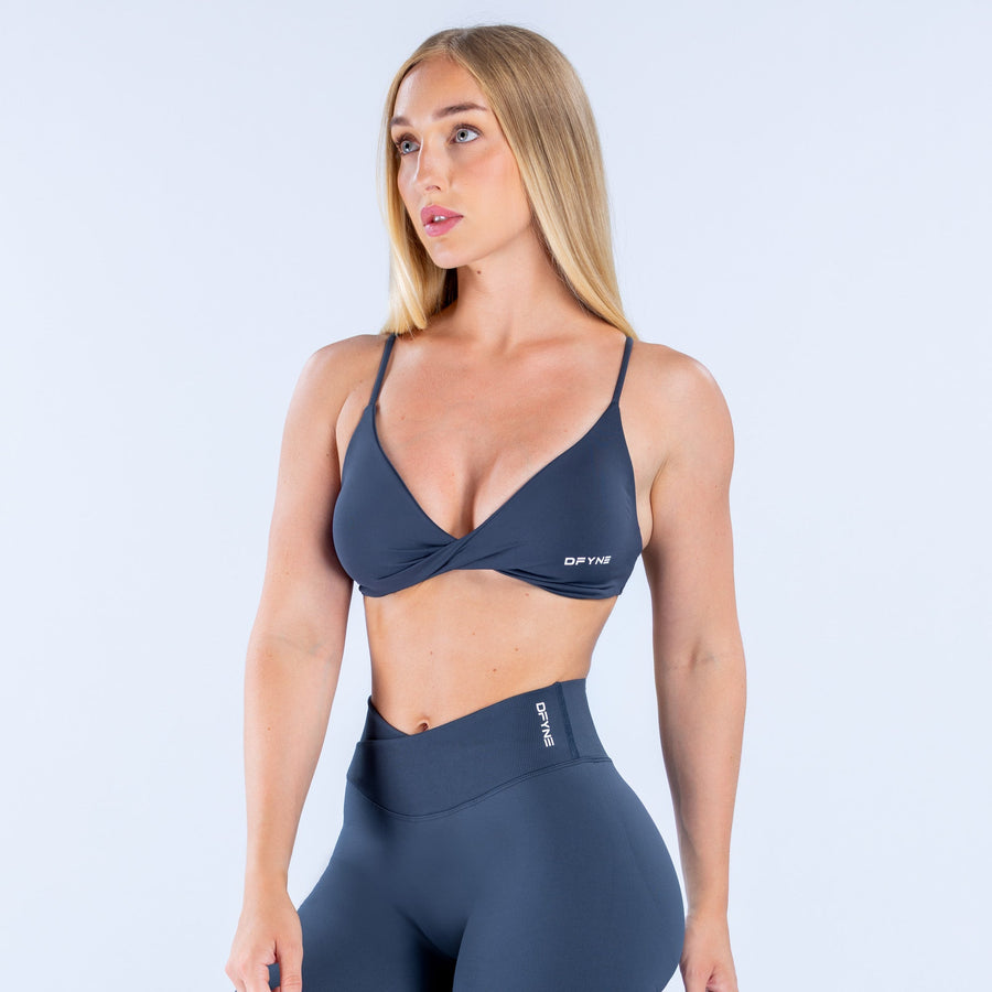 Navy V-neck twist-front sports bra with thin straps and small logo patch